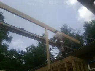 Carpenter setting a ridge beam over a new addition frame — Ice Dam Removal by Roofing Brothers in Home