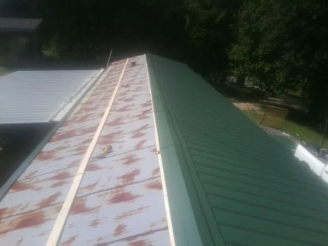 Old rusted panels beside newly installed green metal roofing — Wind Damage Roof Repair by Roofing Brothers in Home