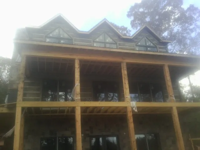 Dormers and porch framing on a large log home under construction — Roof Coating work by our crew in Home