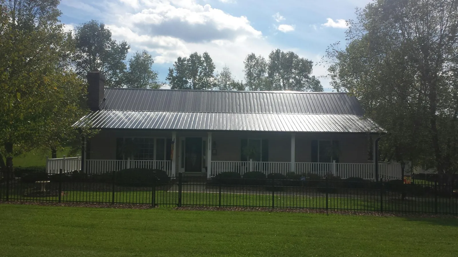 Gray metal roof on a brick ranch with a full width front porch — Gutter Guard Installation work by our crew in Home